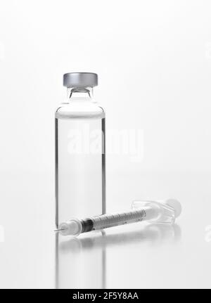 Nahaufnahme eines Fläschchens eines injizierbaren Medikaments oder Impfstoffs und Spritze auf Weiß. Flasche hat kein Etikett. Stockfoto