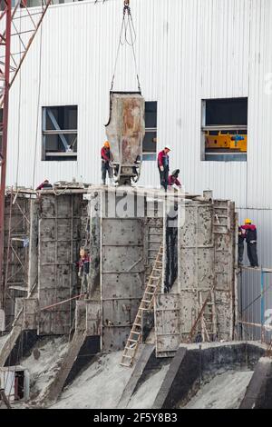 Rudny, Region Kostanay, Kasachstan-Mai 28 2012: Bau eines neuen Industriegebäudes. Arbeiter mit Betoneimer Ausgießformen. Stockfoto