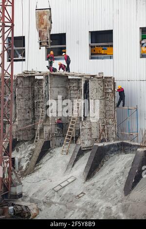 Rudny, Region Kostanay, Kasachstan-Mai 28 2012: Bau eines neuen Industriegebäudes. Arbeiter mit Betoneimer Ausgießformen. Stockfoto