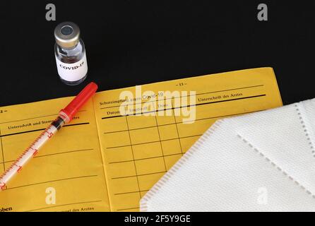 Eine Impfung gegen Covid-19. Impfpass, Impfflasche, Spritze und FFP2-Maske. Stockfoto