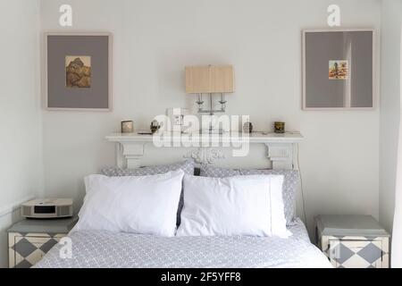 Queensize-Bett mit Kopfteil, Nachttisch und Lampe. Kissen, grauer Faden und Laken. Klassisches gepflegtes Schlafzimmer mit Platz für Text an der Wand Stockfoto