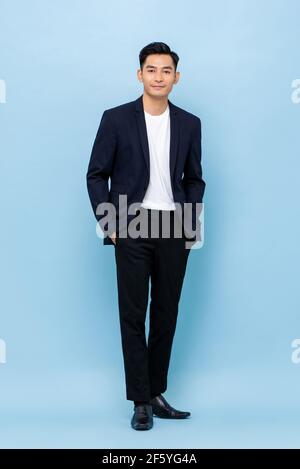 In voller Länge Porträt von glücklich lächelnd junge gut aussehend Südostasiatisch Geschäftsmann steht auf hellblauem Studiohintergrund Stockfoto