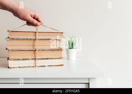 Hand hält einen Stapel von alten Büchern in der Bibliothek, Konzept des Lernens, Studium und Bildung, Konzept der Wissenschaft, Weisheit und Wissen. Hochwertige Pho Stockfoto