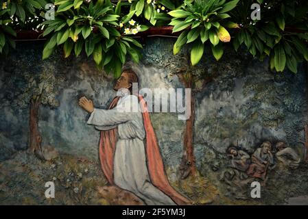 Ein Flachrelief, das Jesus im Garten Gethsemane beim Beten zeigt, das von einem unbekannten Künstler an einer Wand in der Nähe der St. Ignatius Loyola Kirche, Sikka, geschaffen wurde. Stockfoto