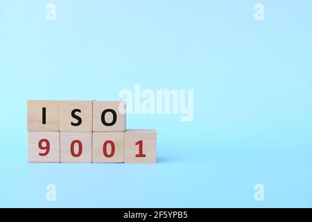 ISO 9001 oder Quality Management Systems Konzept auf Holzblöcken auf blauem Hintergrund. Stockfoto