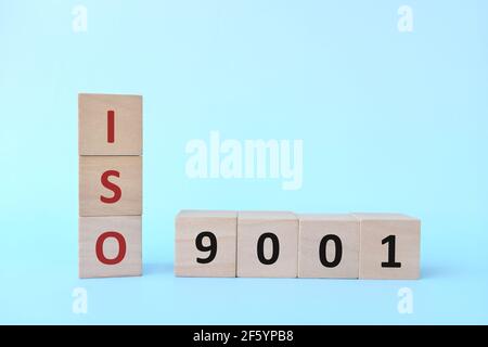 ISO 9001 oder Quality Management Systems Konzept auf Holzblöcken auf blauem Hintergrund. Stockfoto