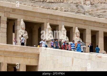 Touristen nähern sich den Osiris-Säulen auf der oberen Terrasse am Totentempel der Hatschepsut bei Deir al-Bahri in der Nähe von Luxor in Ägypten. Stockfoto