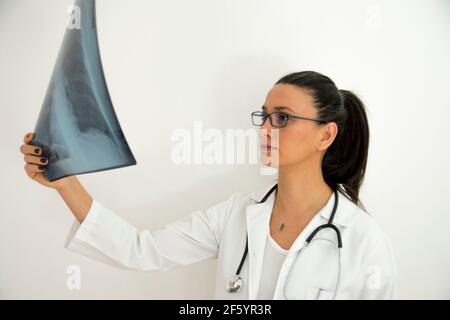 Junge Ärztin mit Brille untersucht Röntgen an ihrer Hand. Selektiver Fokus Stockfoto