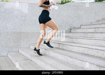 Zugeschnittenes Bild von fit junge Frau mit Handtuch in den Händen Die Treppe hoch laufen Stockfoto