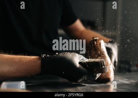 Nahaufnahme eines Mannes in schwarzen Latexhandschuhen, der Schuhbürste putzt, Staub und Schmutz mit dem Finger abbürstet. Stockfoto