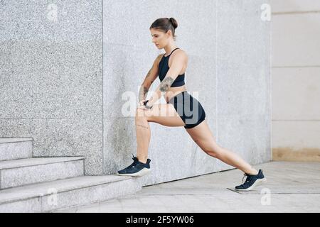 Ernst fit junge Frau setzen Fuß auf Schritt im Freien und Ausfallschritte Stockfoto