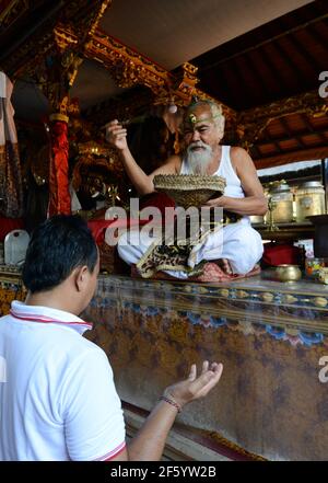 Ein balinesischer Hindu-Priester segnet einen Bräutigam in einer Vorhochzeit-Zeremonie in einem kleinen Tempel in Ubud, Bali, Indonesien. Stockfoto