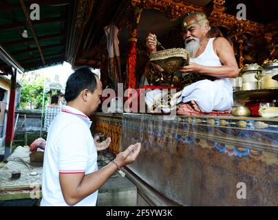 Ein balinesischer Hindu-Priester segnet einen Bräutigam in einer Vorhochzeit-Zeremonie in einem kleinen Tempel in Ubud, Bali, Indonesien. Stockfoto