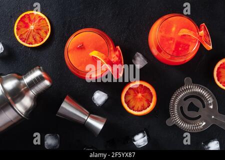 Orangefarbene Cocktails mit Baraccessoires, Overhead-Shot auf schwarzem Hintergrund Stockfoto