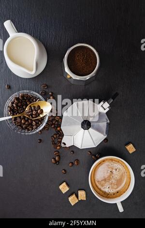 Stillleben mit Mokakapfanne, Kaffeebohnen, Milch, Zucker und frischem heißen Espresso Stockfoto