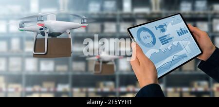 Warehouse Manager mit digitalem Tablet steuert Drohne mit einem Paket. Unbemanntes Lieferkonzept Stockfoto