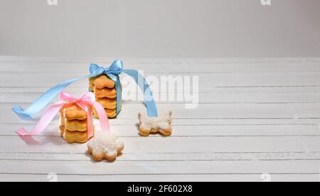 Kekse lockige Blumen und Schmetterling, mit satinfarbenen Bändern verziert und mit Puderzucker bestreut. Auf einer weißen Arbeitsplatte. Blick von vorne. Stockfoto