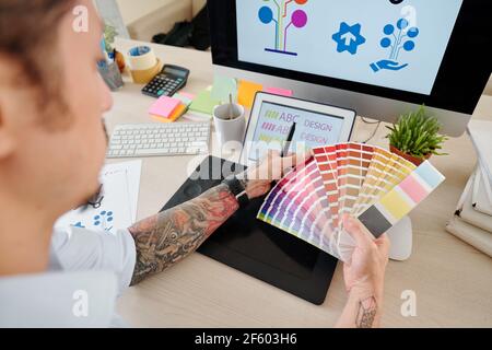 Hände des Grafikdesigners, der die Palette betrachtet und Farbe wählt Für Firmenlogog Stockfoto