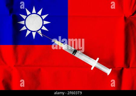Konzept der laufenden Bemühungen der Republik China, COVID-19-Impfstoff mit einer gebrauchsfertigen Spritze unter taiwanesischer Flagge zu liefern und zu verteilen. Stockfoto
