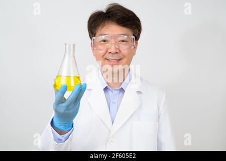 Porträt eines asiatischen Wissenschaftlers mit einem weißen Laborkleid und Handschuhen, der einen experimentellen Behälter in der Hand hält. Stockfoto