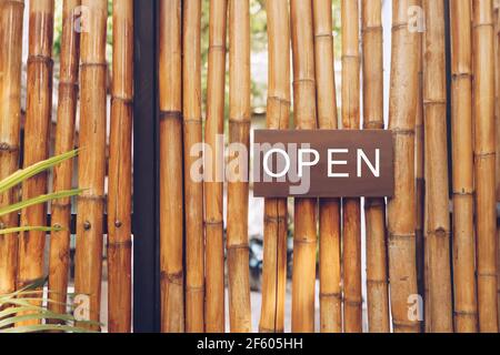 Ein Business-Schild mit der Aufschrift „Öffnen“ auf dem Café oder Restaurant hängt an der Tür am Eingang. Vintage-Farbtonstil. Stockfoto