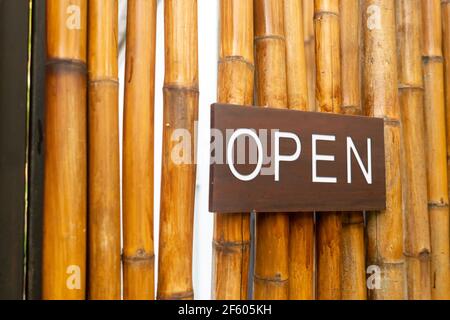 Ein Business-Schild mit der Aufschrift „Öffnen“ auf dem Café oder Restaurant hängt an der Tür am Eingang. Vintage-Farbtonstil. Stockfoto