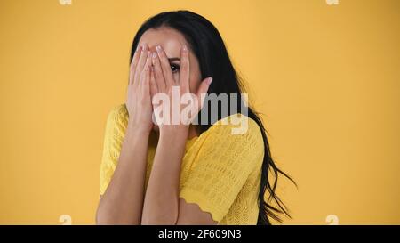 Verängstigte Frau bedeckt Gesicht mit Händen isoliert auf gelb Stockfoto