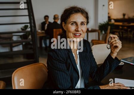 Porträt einer Geschäftsfrau, die lächelt, während sie im Büro sitzt Stockfoto