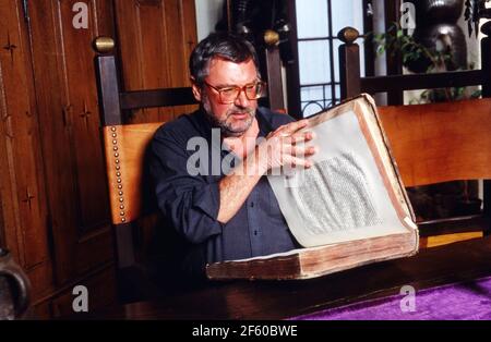Schatzsucher und Enteuerer Hans Jörg Jacobi, der auf der Suche nach dem Nibelungenhort ist, vor einem alten Blättern in seiner Wohnung in Mainz, Deutschland 1992. Stockfoto
