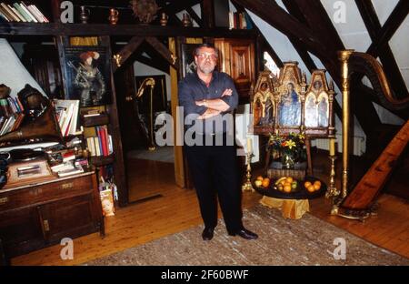 Schatzsucher und Abenteuerer Hans Jörg Jacobi, der auf der Suche nach dem Nibelungenhort ist, vor einem Triptychon Altarbild in seiner Wohnung in Mainz, Deutschland 1992. Stockfoto