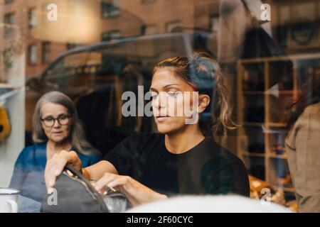 Weibliche Kollegen sahen durch die Glasarbeiten im Bekleidungsgeschäft Stockfoto