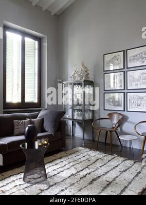 Interieur eines eleganten, zeitgenössischen Wohnzimmers mit zwei skandinavischen Holzstühlen und Bücherregalen, Mailand, Italien Stockfoto