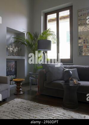 Interieur eines eleganten, zeitgenössischen Wohnzimmers mit zwei skandinavischen Holzstühlen und Bücherregalen, Mailand, Italien Stockfoto