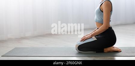 Nicht erkennbare sportliche Dame in Sportbekleidung Training auf Yoga-Matte Stockfoto