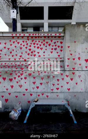 Rote Herzen, die von Mitgliedern trauernder Familien auf der COVID-19 Memorial Wall gegenüber dem Houses of Parliament in Embankment im Zentrum von London gemalt wurden, in Erinnerung an die mehr als 145.000 Menschen, die in Großbritannien an einem Coronavirus gestorben sind. Bilddatum: Montag, 29. März 2021. Stockfoto