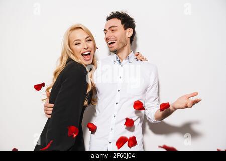 Schöne romantische junge glückliches Paar feiert ein Ereignis zusammen isoliert auf weißem Hintergrund, fallenden Rosenblättern Stockfoto