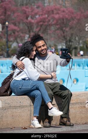 Ein altes Schulpaar nimmt ein Selfie mit einer Polaroid-Kamera auf. Im Flushing Meadows Corona Park in Queens, New York City Stockfoto