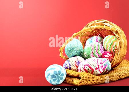 Bunte ostereier verschüttet aus dem Holzkorb mit Stoff auf farbigem Hintergrund. Frohe Ostern Stockfoto