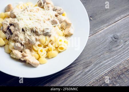 Frische Pasta mit Huhn, Pilzen und Käse auf rustikalem Hintergrund. Selektiver Fokus. Stockfoto