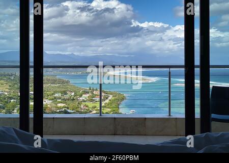Zimmer mit Blick durch Fenster und Balkongeländer auf Plettenberg Bay, Keurboomsrivier und Indischen Ozean, Südafrika Stockfoto