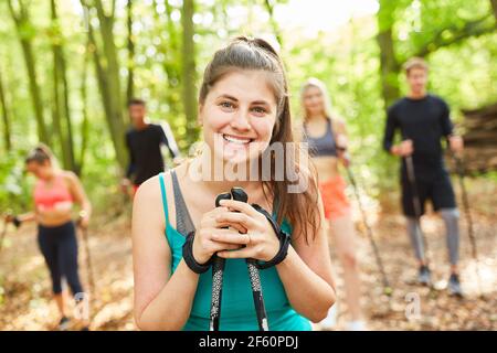 Lächelnde junge Frau mit Freunden beim Nordic Walking in der Natur Im aktiven Urlaub Stockfoto