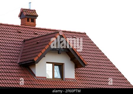 Nahaufnahme des neuen orangefarbenen Daches mit Kamin und kleinem modernen Fenster. Konzept des modernen Dachs mit stilvollen kleinen braunen Fenster. Stockfoto