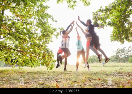 Gruppe von Freunden macht hohe fünf im Sprung nach Gemeinsam im Sommer ein Fitnesstraining Stockfoto