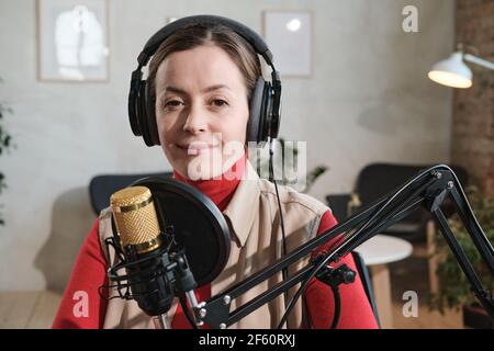 Porträt einer jungen Frau in Kopfhörer sprechen im Mikrofon während Rundfunk sie arbeitet im Radio Stockfoto