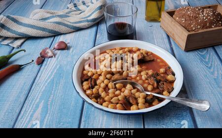 Rezept für Muscheln mit Kichererbsen, Glas Rotwein und Brot, typisch spanisches Gericht, fertig zum Essen Stockfoto