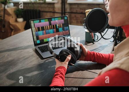 Nahaufnahme einer Frau, die an ihrem Arbeitsplatz sitzt und arbeitet Laptop während der Luft im Radio Stockfoto