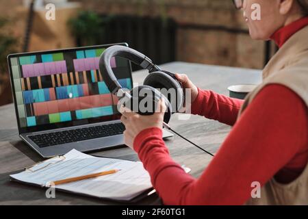 Nahaufnahme einer Frau in Kopfhörern, die mit am Tisch sitzt Laptop und Aufnahme Podcast für Online-Show im Radiostudio Stockfoto