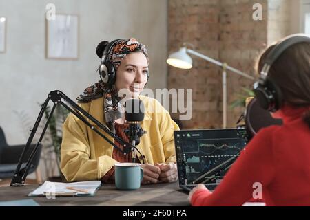 Weibliche Radio-dj in Kopfhörer sprechen im Mikrofon und Interviews Ein Gast während der Sendung im Radio Stockfoto
