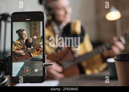 Junge Sängerin spielt auf der Gitarre und singt ein Lied und Aufzeichnung auf dem Mobiltelefon Stockfoto
