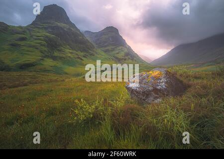 Moody, atmosphärische Berglandschaft der üppigen, grünen Three Sisters of Glencoe bei einem Sommer-Sonnenuntergang oder Sonnenaufgang in den Scottish Highlands, Scotlan Stockfoto